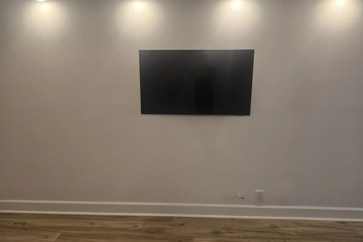 Gallery-style TV wall mounting with zero visible cables under custom spotlighting